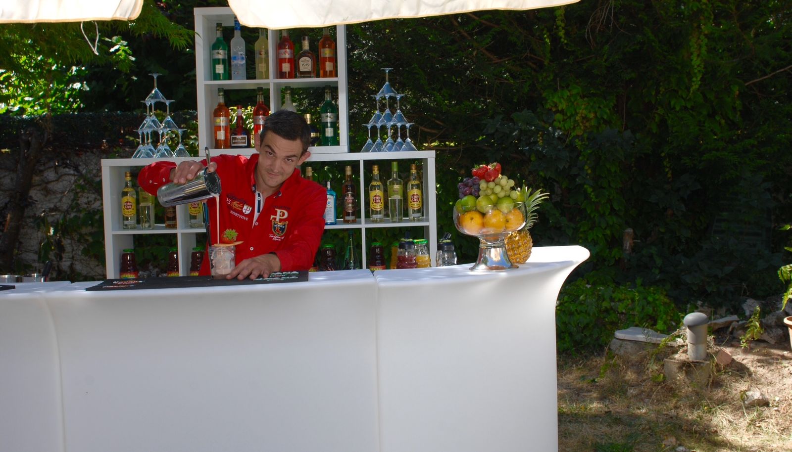 Barman versant un cocktail au shaker derrière un bar mobile en plein jour
